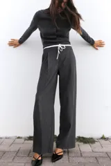 Pantalón ancho gris con textura de espiga, tiro alto, doble cintura elástica ajustable con cordón, pinzas frontales, bolsillos delanteros y falso bolsillo de vivo en la espalda.