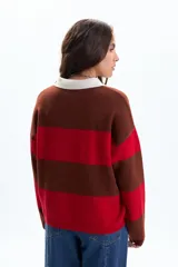 Sweater de tejido de punto con diseño a rayas horizontales anchas en colores rojo, marrón oscuro y beige claro en el cuello. Posee cuello polo y tapeta con botones.