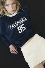 Falda pantalón color crema de tiro bajo con cintura asimétrica, bolsillos delanteros de vivo y cierre lateral con cremallera oculta.