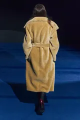 Abrigo largo color camel con efecto piel de oveja, cuello solapa, manga larga, bolsillos delanteros y cinturón ajustable con lazadas. Forro interior.