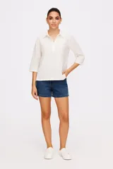 Blusa blanca de algodón con bordado tipo broderie, corte holgado y cuello camisero.