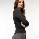 Camiseta negra cropped de manga larga con efecto arrugado en los laterales.