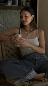 Collar con dije dorado irregular con agujero central, colgando de cordón negro ajustable.