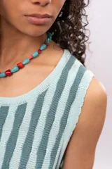 Vestido tejido a rayas verticales en tonos celeste y gris, sin mangas y largo a la rodilla. Incluye cinturón tejido con flecos.