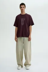 Remera color bordó de corte holgado con cuello redondo y mangas cortas. Estampado frontal con la frase "Handle with care".