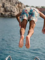 Short de baño blanco con estampado de hojas de palmera en tonos verde, rojo y amarillo.