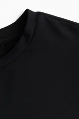 Remera negra entallada de punto suave con cuello redondo fino ribeteado.