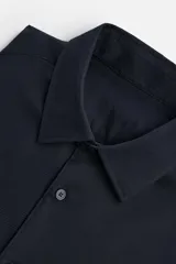 Camisa blanca de corte regular, cuello italiano, manga larga con puños abotonados y cierre frontal con botones.