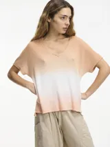 Remera color durazno con degradé blanco, de punto con escote en V y mangas cortas.
