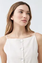 Chaleco color beige con botones de nácar, sin mangas y con bolsillos frontales.