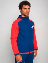 Campera deportiva con capucha, azul con mangas y hombros rojos, cierre frontal y escudo del Club Nacional de Football en el pecho.
