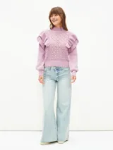 Sweater lila de tejido calado con cuello alto y mangas largas abullonadas con volados.