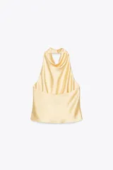 Top color amarillo claro de satén con cuello halter y espalda descubierta. Cierre trasero con botones ocultos.