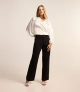 Blusa blanca amplia de viscosa, con lazo delantero, mangas largas abullonadas y canesú con encaje richelieu.