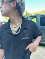 Camisa negra de manga corta con cuello, confeccionada en tejido texturizado (tipo waffle o piqué). Presenta un bordado en la espalda con el texto "Ittai Stars" en hilo blanco.