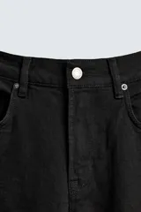 Pantalón de jean negro, corte slim fit, con tiro medio, cinco bolsillos, efecto lavado y cierre frontal con cremallera y botón.
