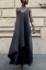 Vestido midi negro de satén con escote en pico, tirantes finos y aplique dorado con cadena en el hombro.