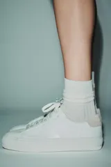 Zapatillas deportivas blancas con detalle de pespuntes en el cuerpo y suela de plataforma.