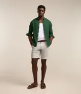 Bermuda de hombre en lino color gris claro, de corte recto, con textura discreta, bolsillos laterales y cierre frontal con botón y cremallera.