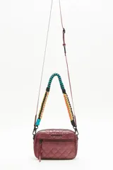 Bandolera negra de nylon matelassé con correa larga regulable y correa corta desmontable de cordones trenzados multicolores. Tiene cierre superior, bolsillo frontal con cierre, bolsillo trasero y dos bolsillos internos.