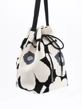Bandolera tipo bucket con estampado de flores en blanco y negro, cierre con cordón ajustable y correa larga de hombro.
