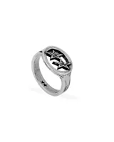 Anillo de metal plateado con diseño envejecido. La parte superior presenta un bisel ovalado con dos estrellas caladas en relieve. El aro del anillo tiene detalles grabados y dos estrellas pequeñas en relieve en la parte inferior.