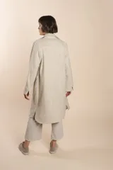 Camisa larga color crema con rayas verticales finas en gris, con botones dorados y bolsillo plaque en la delantera.