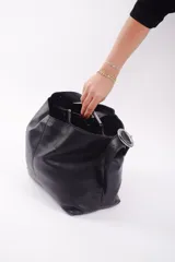 Bolso marrón de cuero con textura, tipo shopper, con correa regulable para usar al hombro o cruzada. Tiene un bolsillo espacioso con cierre que divide el interior en tres compartimentos.