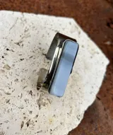 Pulsera rígida de alpaca plateada con piedra rectangular color celeste con vetas horizontales.