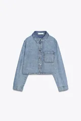 Camisa corta de denim celeste, con cuello solapa, manga larga, bolsillo delantero de plastrón y cierre frontal con botones metálicos.