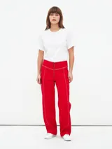 Pantalón rojo de corte recto con cierre frontal y costuras a la vista.