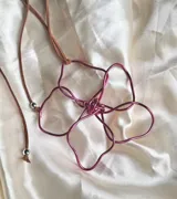 Collar con dije de flor hecho a mano con alambre dorado y cordón negro.