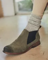 Botines Chelsea de cuero negro con elástico lateral y suela marrón.