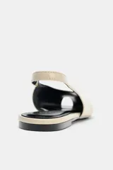 Zapato plano destalonado color beige, con punta abierta, tira trasera con elástico ajustable y suela a contraste de color.