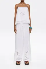 Pantalón blanco de corte ancho con cintura elástica y bordado en la parte inferior de la pierna.