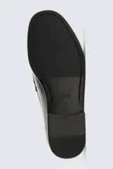 Mocasín de vestir de cuero color verde oscuro, con borlas decorativas en el empeine, punta redondeada y suela con ligero tacón.