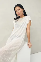 Top largo color blanco, confeccionado en tejido liviano con transparencia y caída fluida.