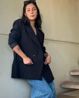 Blazer negro de corte oversize, con solapas de muesca, cierre cruzado con doble botonadura y bolsillos delanteros con solapa.