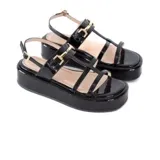 Sandalias negras de charol con plataforma de 5 cm, tiras frontales y pulsera ajustable al tobillo con detalle metálico dorado.