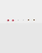 Set de tres pares de aros pasantes: un par de aros con forma de corazón dorado, un par de aros con forma de flor roja con strass y un par de aros de perlas.