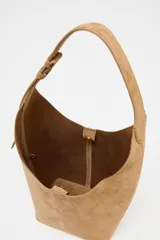 Bolso tipo saca de cuero color marrón claro, con asa de hombro ajustable y cierre imantado. Incluye cartera interior con cierre de cremallera metálica.