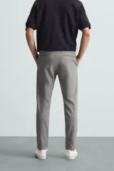 Pantalón largo de vestir gris claro con estampado de cuadros, corte slim fit y cintura elástica. Confeccionado en tejido con alta elasticidad, bolsillos frontales y cierre frontal con cremallera y botón.