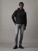 Buzo negro de poliéster con capucha y cordones ajustables, puños y dobladillo con punto canalé, corte relaxed y cintas decorativas con el logo de Calvin Klein repetido en las mangas.