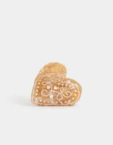 Broche para el pelo en forma de corazón color crema con diseño de lunares y arabescos en blanco.