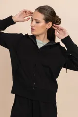 Chaqueta deportiva negra con cierre frontal, capucha con cordones ajustables y bolsillos laterales.