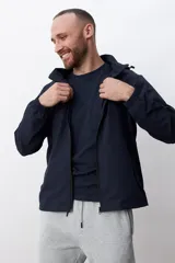 Campera deportiva negra con capucha y cierre frontal.