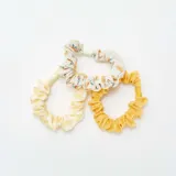 Pack de tres coleteros para el cabello, uno liso color amarillo, uno a cuadros amarillo y blanco, y uno estampado con limones.