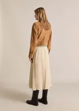 Chaqueta marrón de cuero gamuzado, con cuello camisero, cierre frontal con botones, dos bolsillos de parche delanteros y puños abotonados.