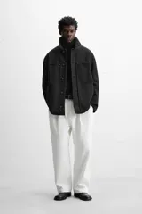 Parka negra de algodón con cuello solapa de cuero sintético, corte recto, acolchada y con cierre frontal de botones.