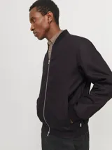 Campera bomber negra de tejido liviano de lino y algodón, con cuello tipo baseball, cierre con cremallera, mangas largas con puños de canalé y bolsillos delanteros.